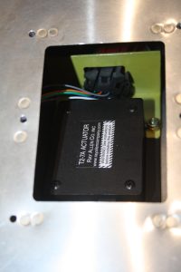 Trim tab servo in place showing the connector bracket, connector and one of the elastic lock nuts.